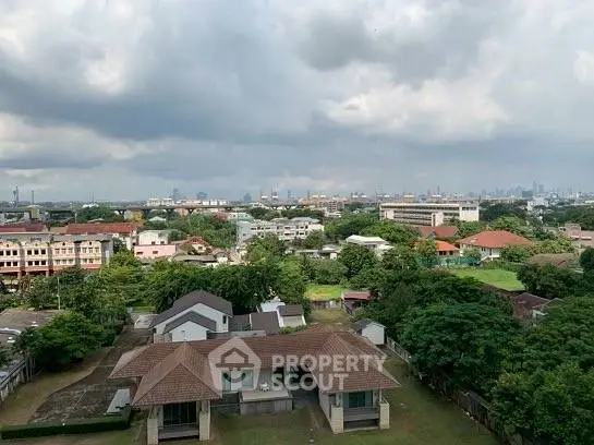 Scenic cityscape view with residential houses and lush greenery under a cloudy sky.