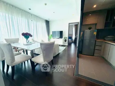 Spacious modern living room with dining area and open kitchen, featuring elegant decor and natural light.