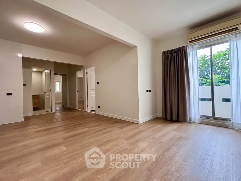Spacious modern living room with wooden flooring and large window for natural light.