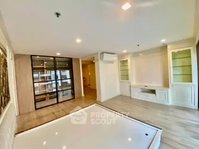 Spacious modern living room with elegant built-in shelves and glass partition in a luxury apartment.