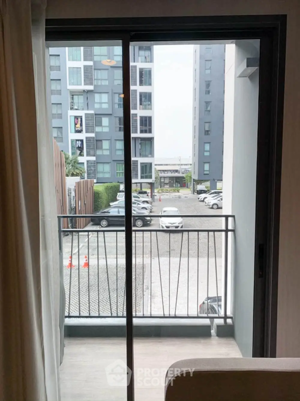 Modern apartment balcony with view of parking and adjacent buildings.