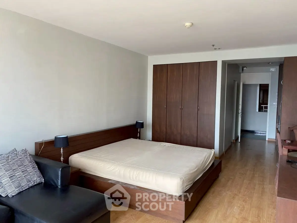 Spacious bedroom with modern wooden furniture and ample natural light.