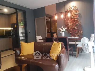 Stylish living room with modern decor and open kitchen layout, featuring elegant lighting and cozy seating.