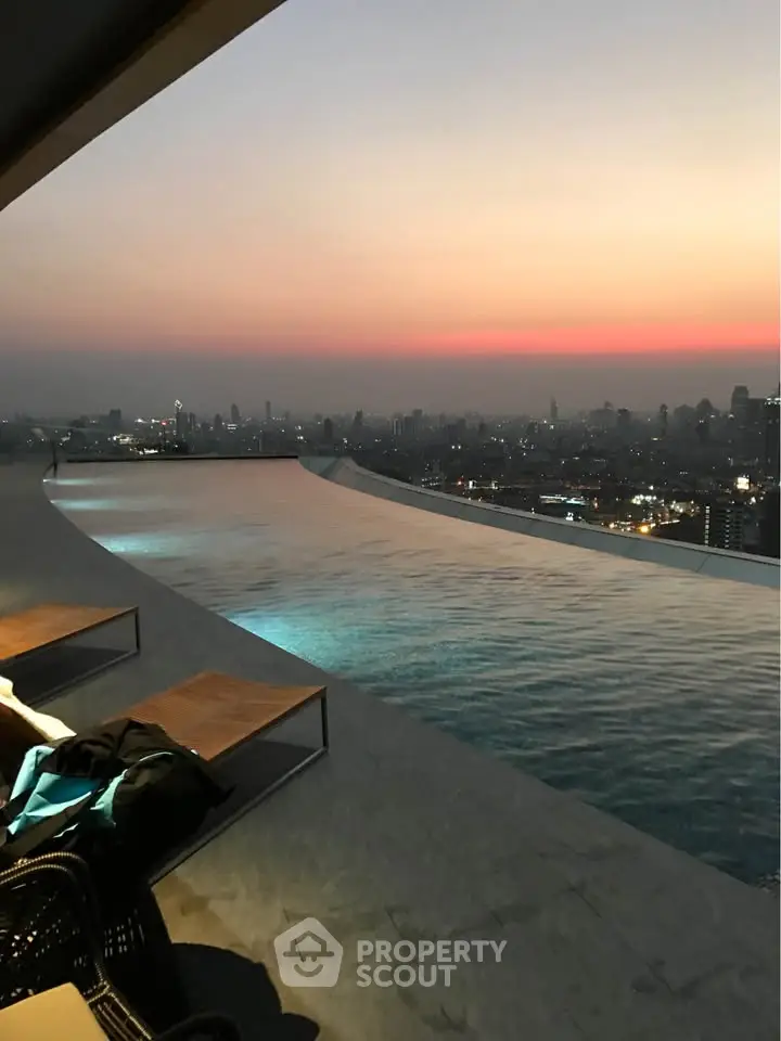 Stunning rooftop infinity pool with breathtaking city skyline view at sunset.