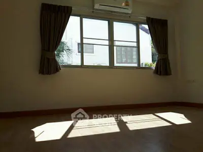 Spacious sunlit room with large window and air conditioning, perfect for a cozy living space.