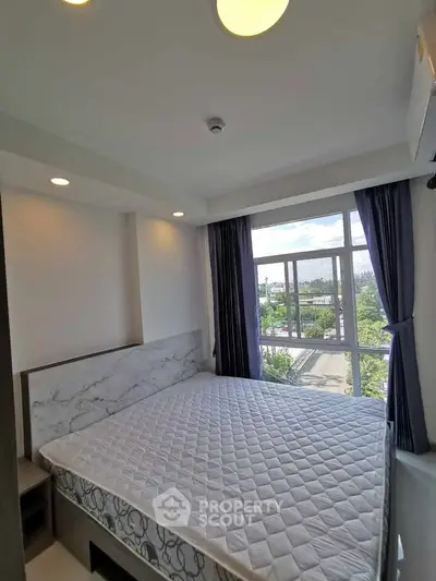 Bright bedroom with large window and modern decor in a high-rise apartment.