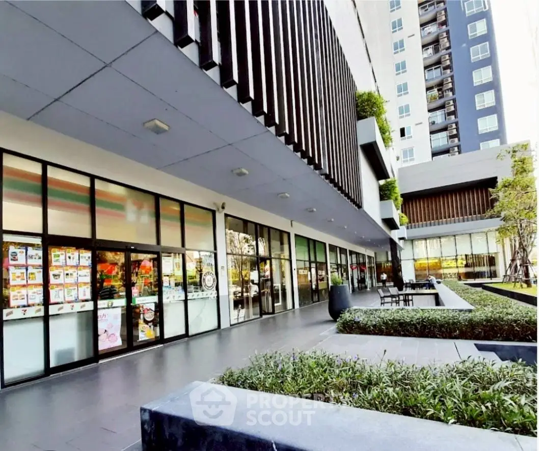 Modern apartment building exterior with landscaped garden and seating area.