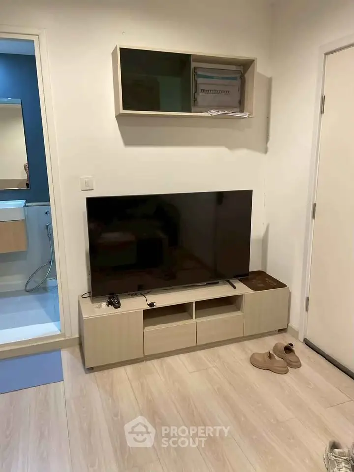 Modern living room with sleek TV stand and wall-mounted cabinet, adjacent to a stylish bathroom.