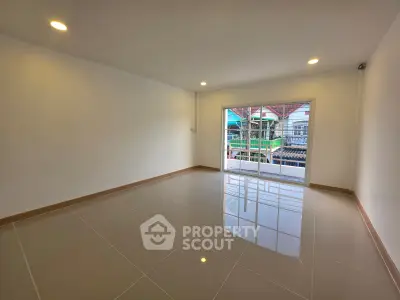 Spacious empty room with glossy tiled floor and large window offering natural light.