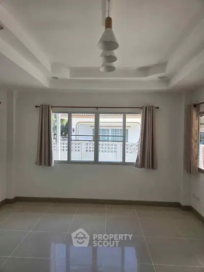 Spacious unfurnished room with large window and modern lighting, ideal for customization.