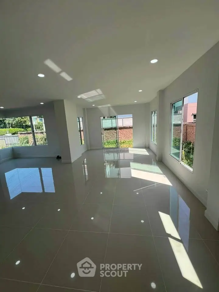 Spacious sunlit living room with glossy tiled floors and large windows