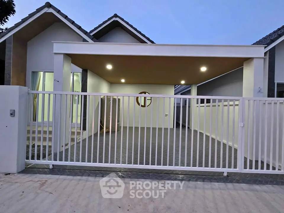 Modern single-story house with spacious carport and sleek white fence.