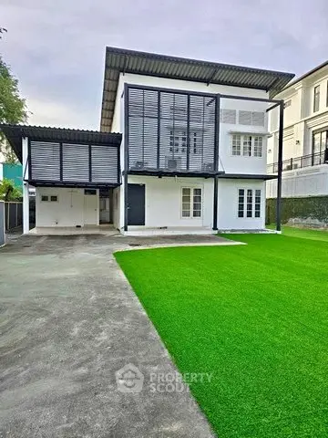 Modern two-story house with sleek design and spacious driveway, featuring lush green artificial turf.