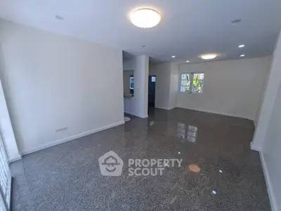 Spacious open-plan living room with glossy floors and ample natural light.