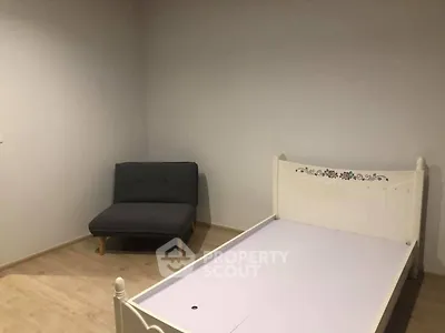 Minimalist bedroom with single bed and cozy chair, perfect for a serene retreat.
