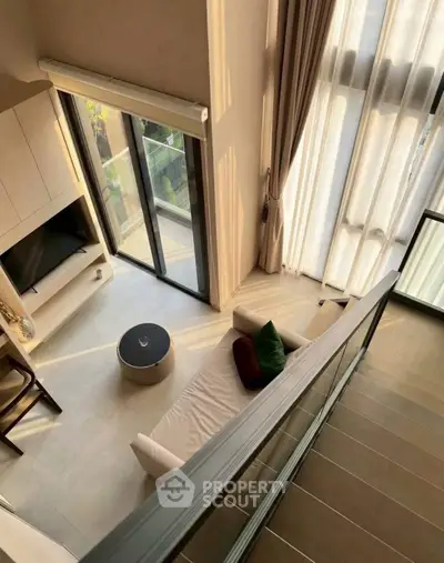 Modern duplex living room with high ceilings and large windows offering natural light.
