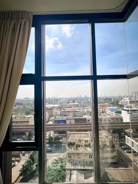 Stunning cityscape view from a high-rise apartment window, showcasing urban skyline and blue skies.