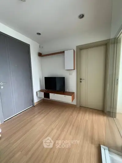 Modern living room with sleek TV setup and wooden flooring, perfect for cozy relaxation.