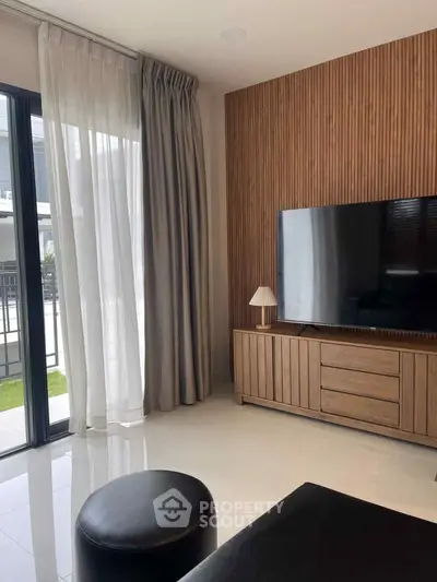 Modern living room with sleek TV setup and stylish wooden paneling, featuring floor-to-ceiling windows.