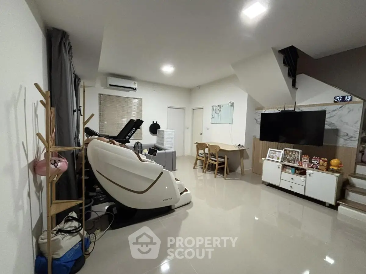 Spacious living room with modern decor and massage chair, ideal for relaxation and entertainment.