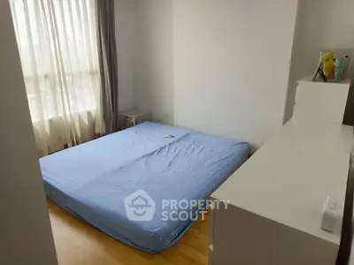 Cozy bedroom with natural light and minimalist decor, featuring a comfortable bed and sleek white furniture.