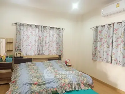 Cozy bedroom with floral curtains and air conditioning, perfect for relaxation.