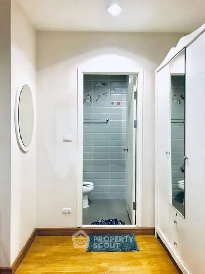 Cozy bathroom entrance with modern white wardrobe and wooden flooring