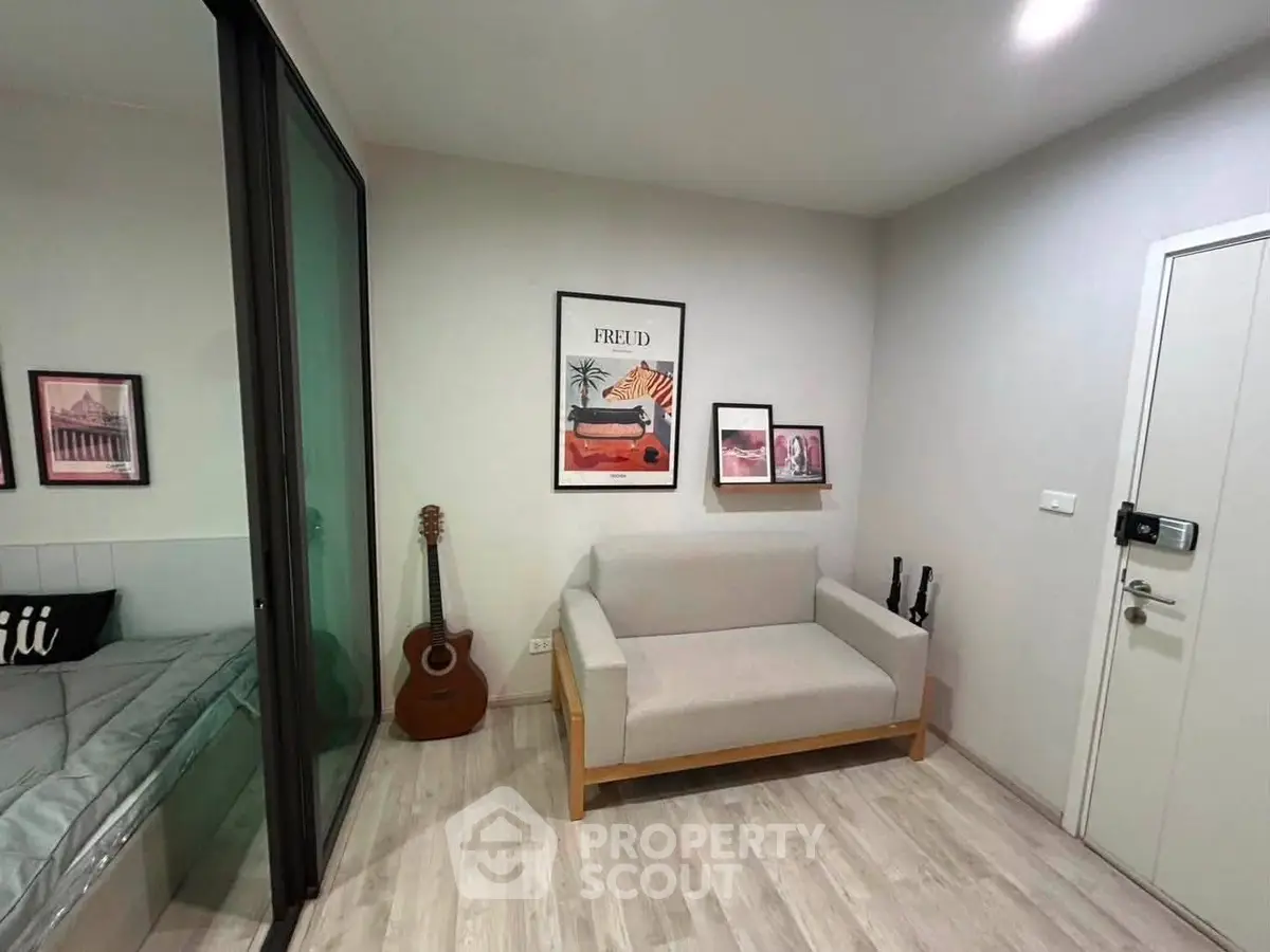 Modern living room with cozy sofa, guitar, and stylish wall art in a contemporary apartment.