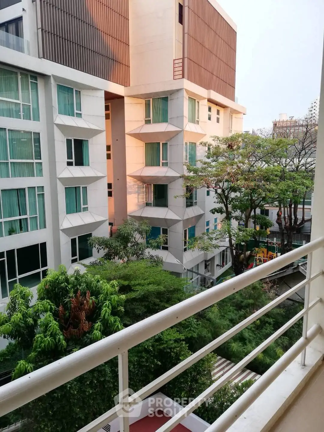 Modern apartment building with lush greenery and spacious balcony view.