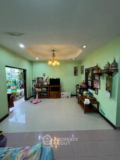 Spacious living room with elegant chandelier and garden view, perfect for family gatherings.
