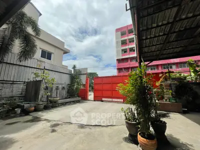 Spacious outdoor area with gated entrance and lush greenery, ideal for residential or commercial use.