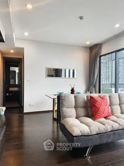 Modern living room with stylish sofa and dining area, featuring large windows and elegant decor.