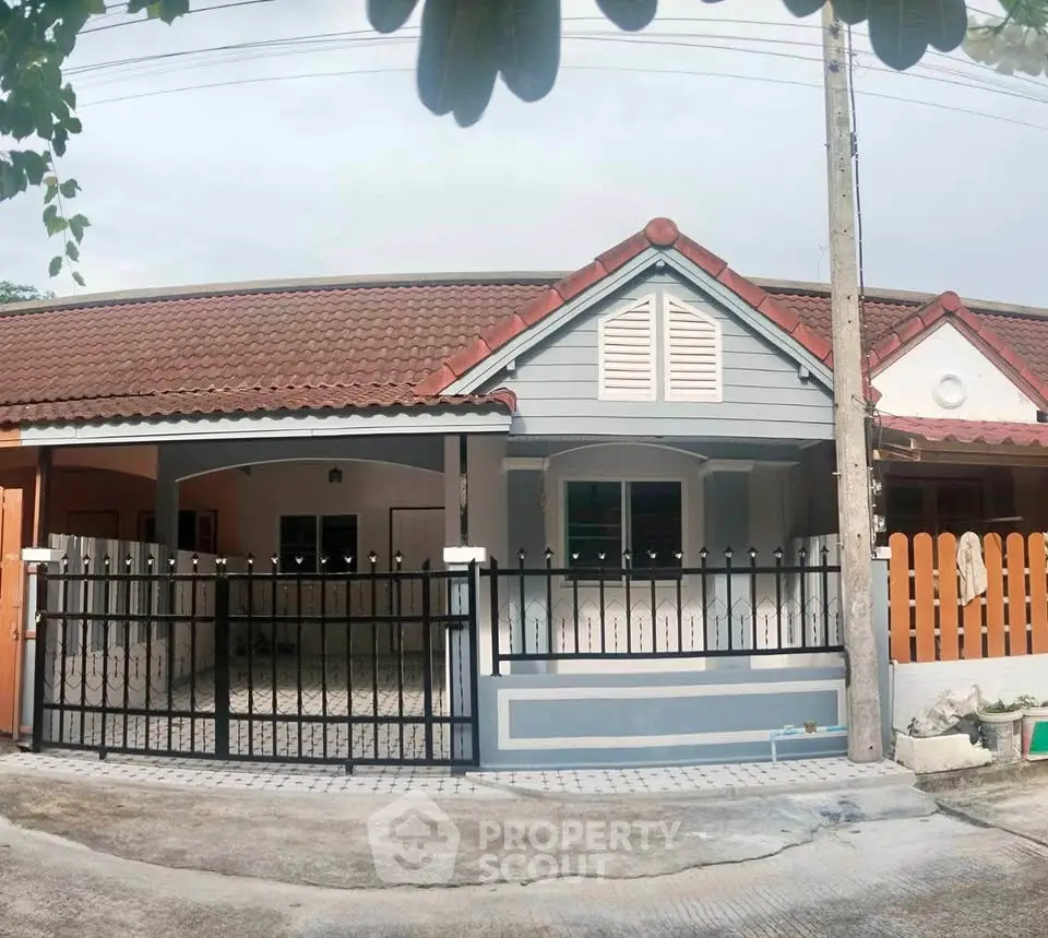 Charming single-story home with tiled roof and gated driveway in a peaceful neighborhood.