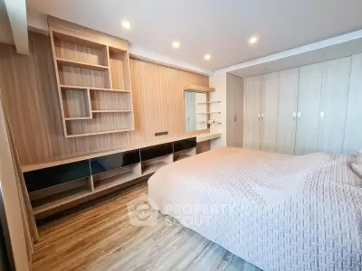 Spacious modern bedroom with elegant wooden accents and ample storage space.