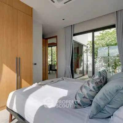 Modern bedroom with large window and stylish decor, offering a serene garden view.