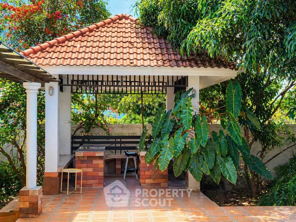 Charming outdoor gazebo with tiled roof and lush garden surroundings, perfect for relaxation and entertaining.