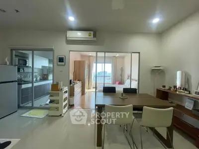 Modern open-plan living and dining area with kitchen and bedroom view.