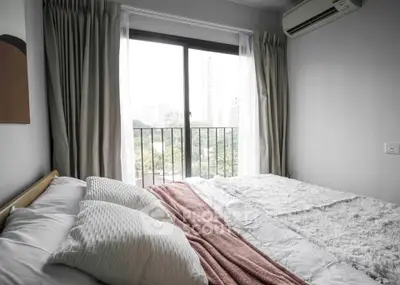 Cozy bedroom with large window and city view, featuring modern decor and air conditioning.