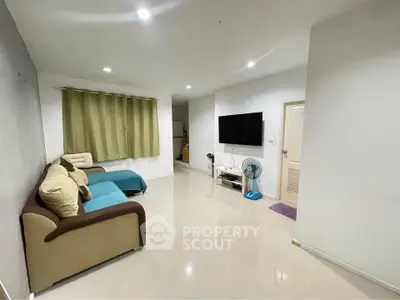 Spacious living room with modern decor and wall-mounted TV in a cozy apartment.
