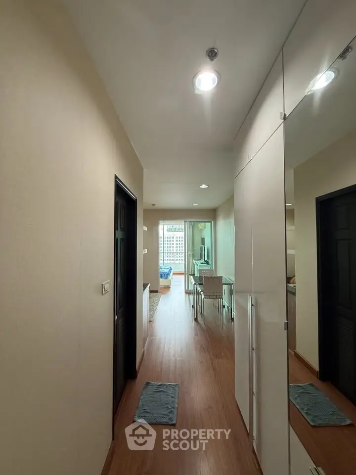 Modern apartment hallway leading to a bright living area with wooden flooring and stylish decor.