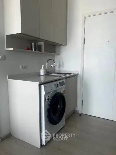 Modern laundry area with washing machine and sleek cabinetry in a contemporary home.