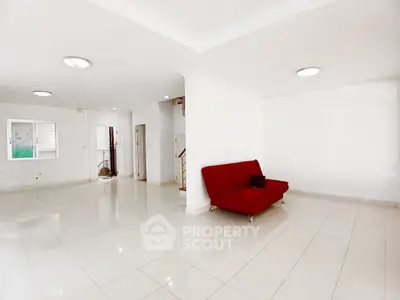 Spacious open-plan living area with red sofa and tiled flooring