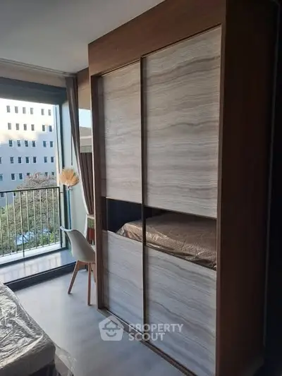 Modern bedroom with large wardrobe and balcony view, perfect for urban living.