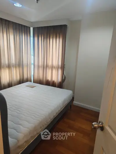 Cozy bedroom with natural light and wooden flooring, perfect for relaxation.