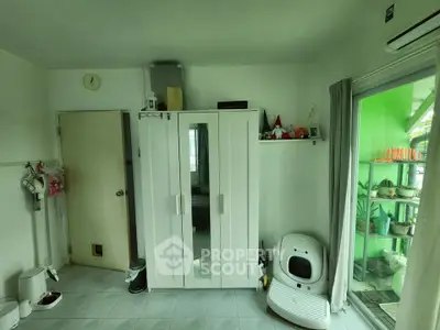 Cozy bedroom with white wardrobe and pet amenities, featuring a sliding door to a green balcony.