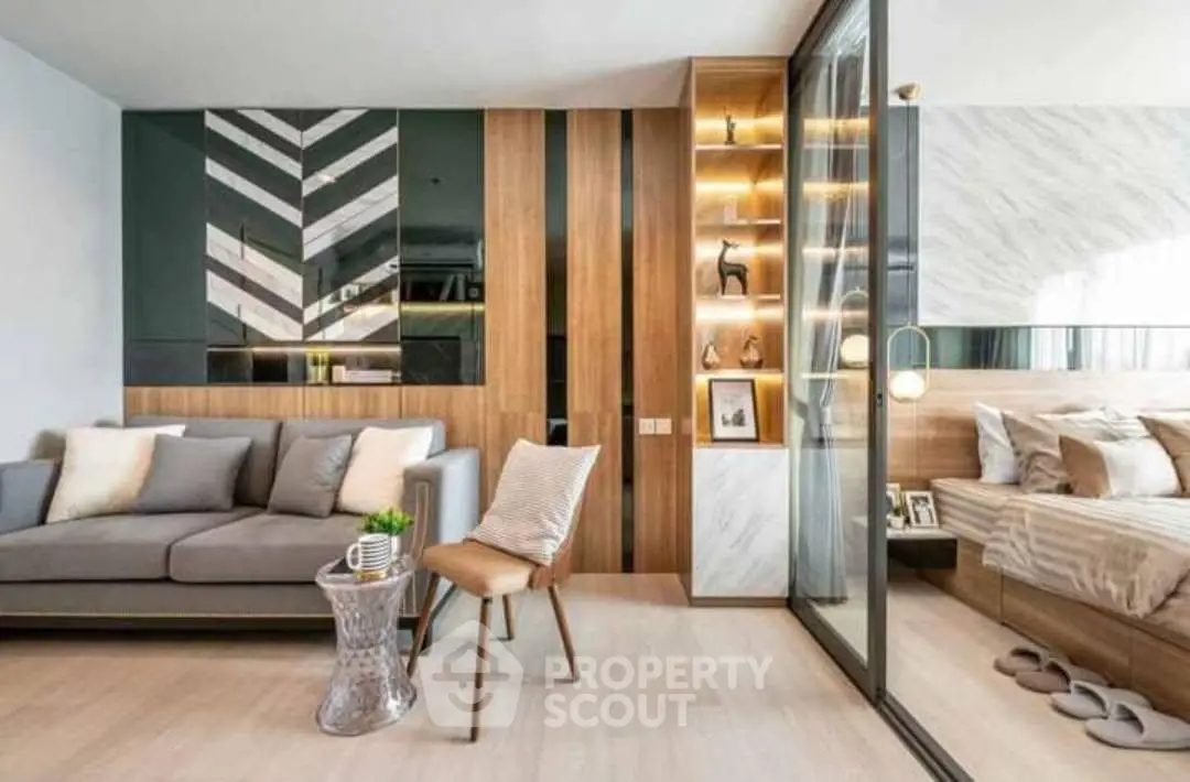Modern living room with stylish decor and adjacent bedroom, featuring sleek furniture and warm lighting.