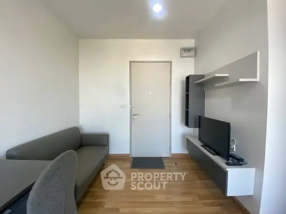 Modern living room with sleek furniture and wall-mounted TV in a compact apartment.