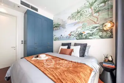 Stylish bedroom with blue wardrobe and tropical mural accent wall.