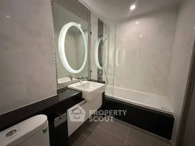 Modern bathroom with sleek design, featuring a bathtub and illuminated mirror.