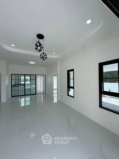 Spacious modern living room with sleek tile flooring and stylish lighting fixtures.